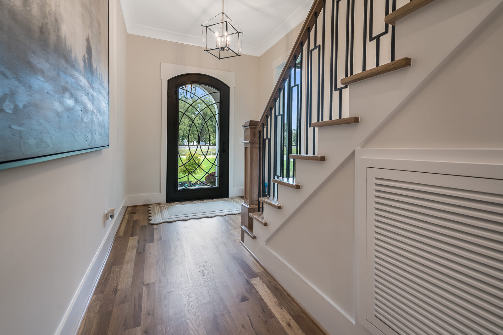 Arched iron-glass entry and oak staircase in a Gemstone home