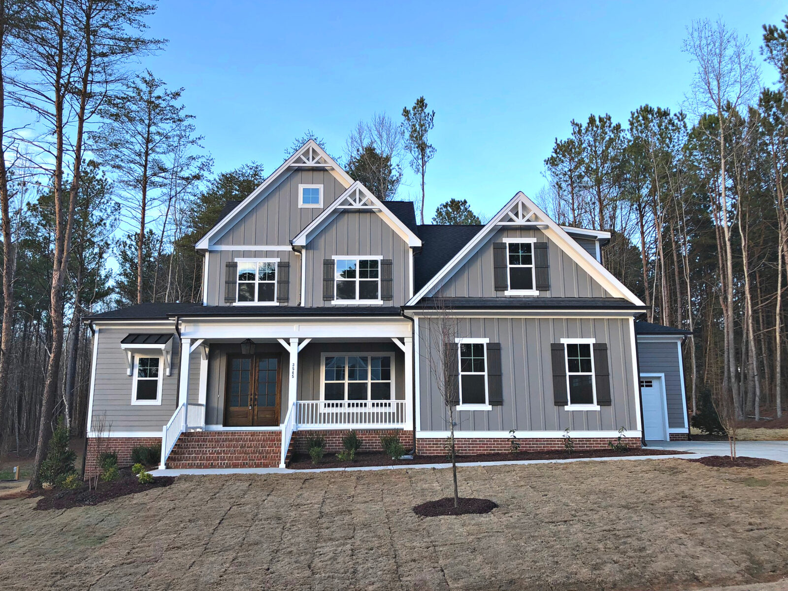 A completed Gemstone custom home at blue hour with the entry and porch lit