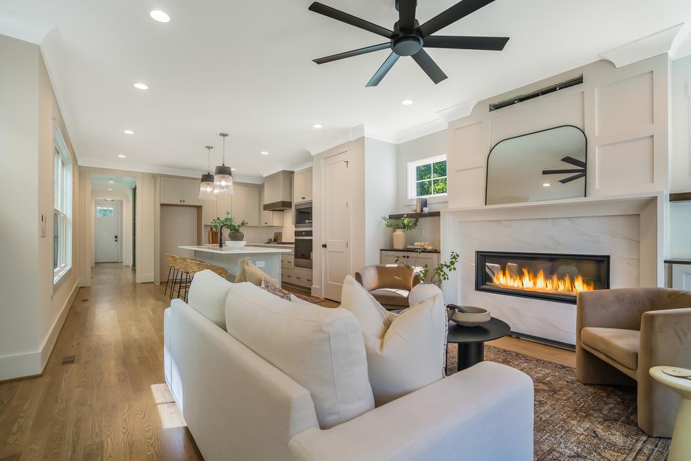 A living room with a linear fireplace, a cream sofa and two blush armchairs