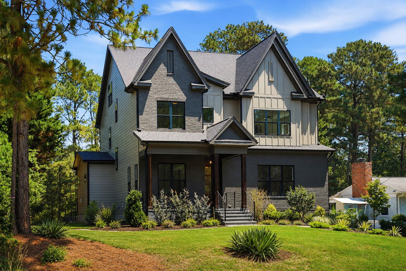 A two-story home with dark brick, board and batten siding, steep gables and a landscaped front yard