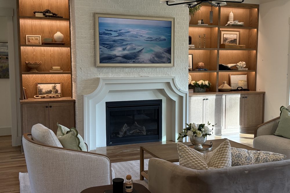 A painted brick fireplace with an arched plaster surround between lit oak built-ins