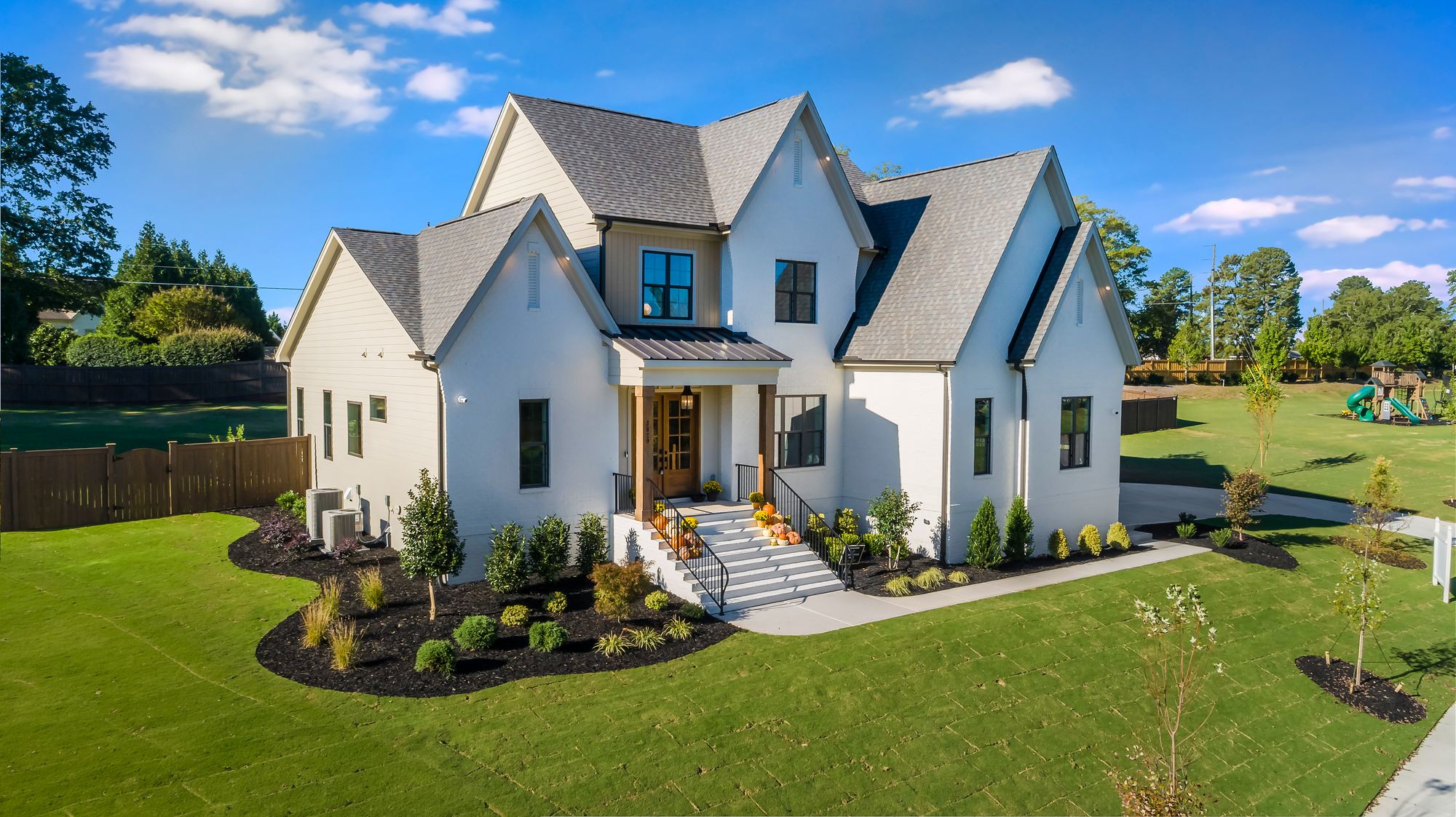 The Onyx at McLaurin Farms, a white brick home with steep gables and a cedar-post porch, from the air