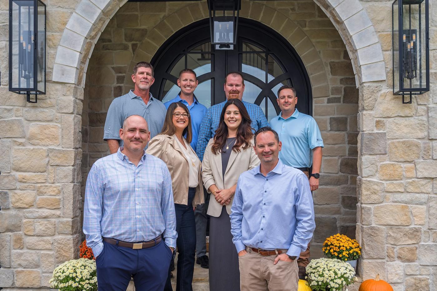 The Gemstone Homes team standing under an arched stone entry