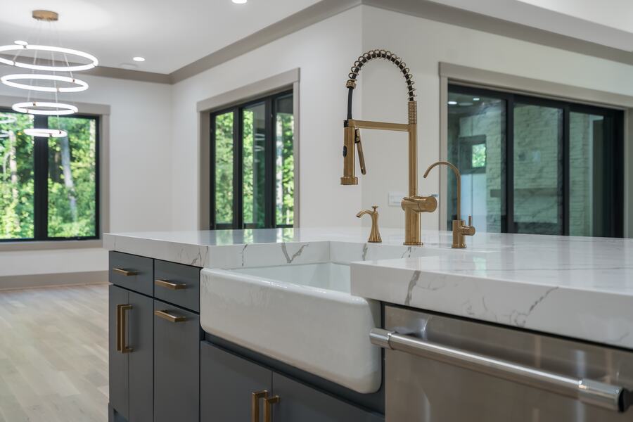 Kitchen island with a farmhouse sink and brass faucet in a Gemstone custom home