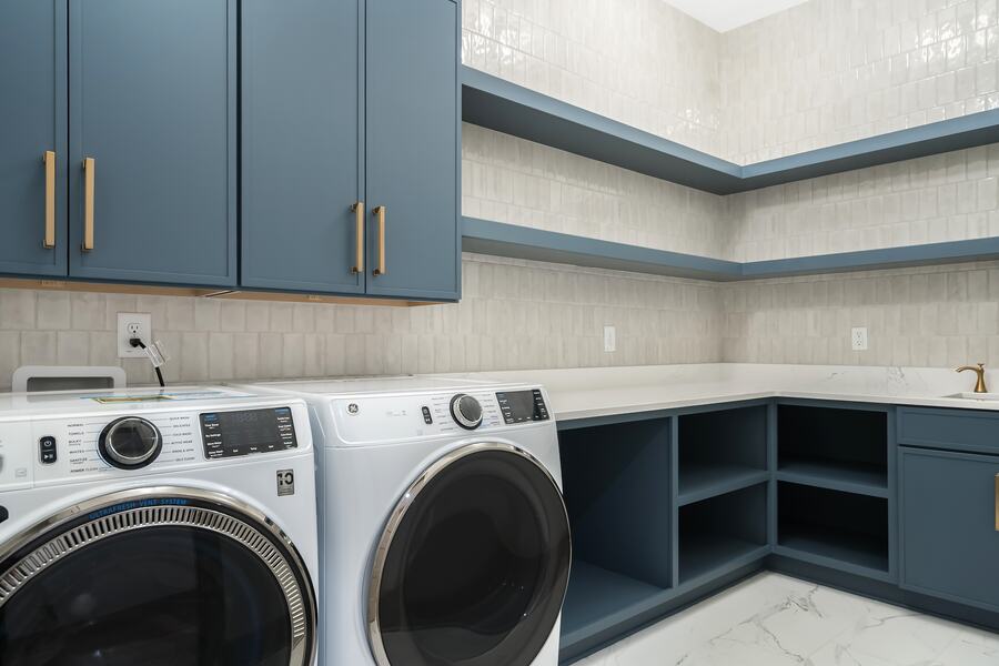 Laundry room with navy cabinetry and brass hardware in a Gemstone custom home
