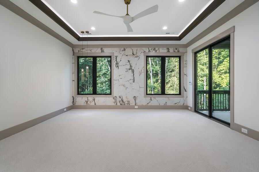 Primary bedroom with a marble accent wall in a Gemstone custom home