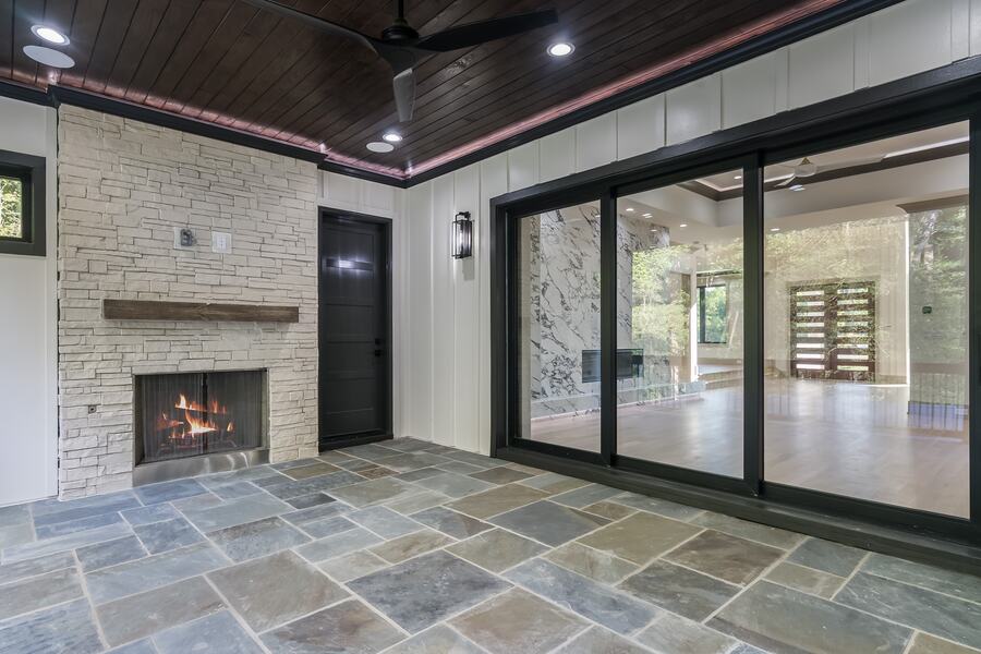 Screened porch with a stone fireplace and slate floor in a Gemstone custom home