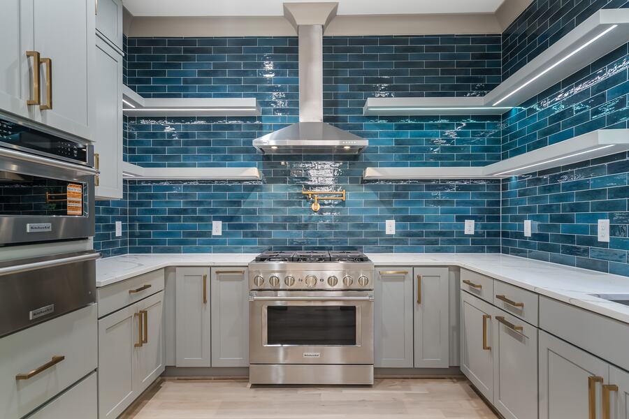 Scullery with teal tile, brass fixtures, and a professional range in a Gemstone custom home