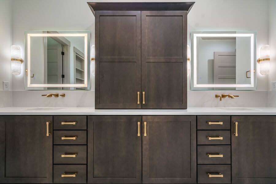 Primary vanity with backlit mirrors and alabaster sconces in a Gemstone custom home
